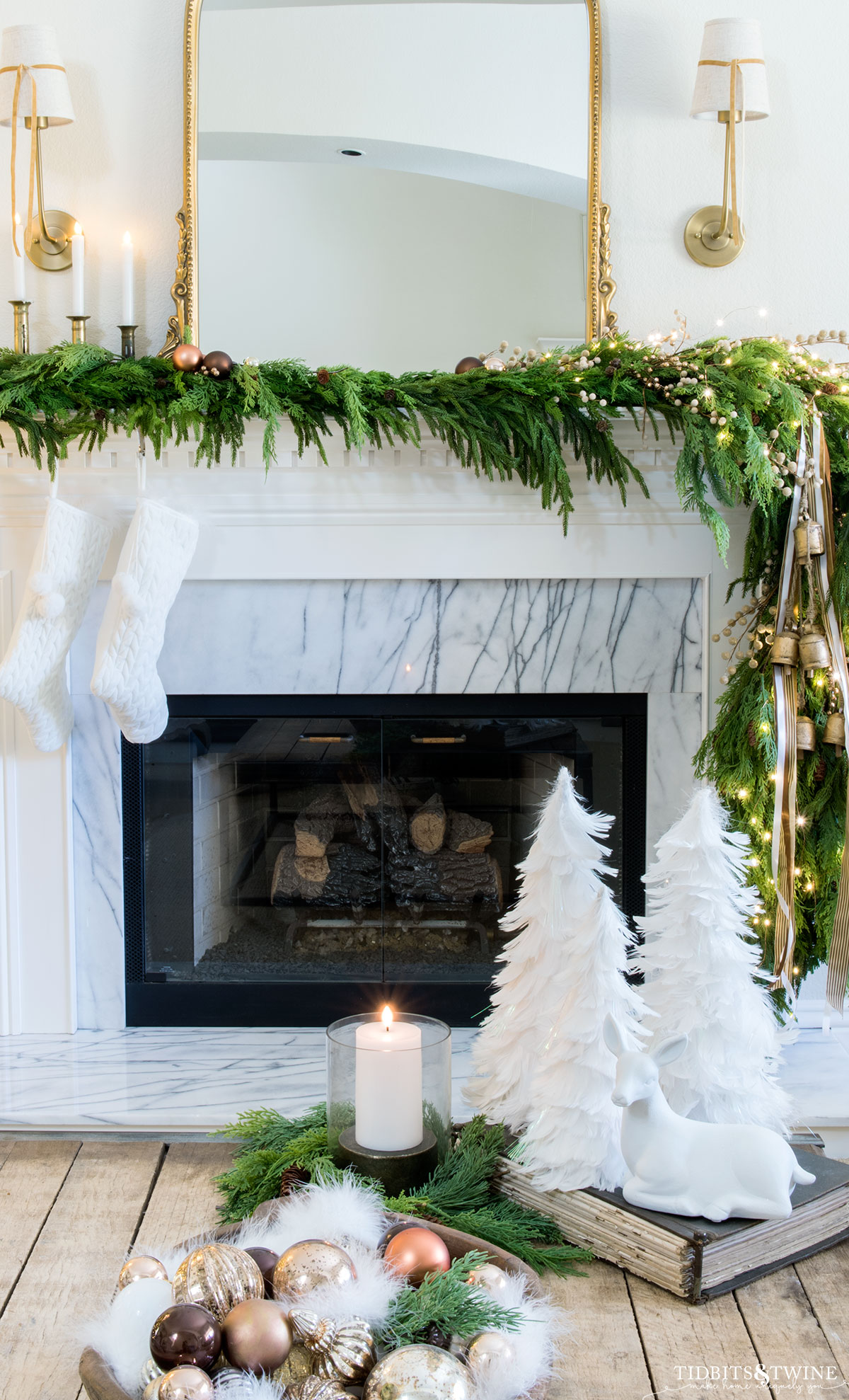 white french christmas mantel with gold mirror above and asymmetrical garland with bells and ribbon