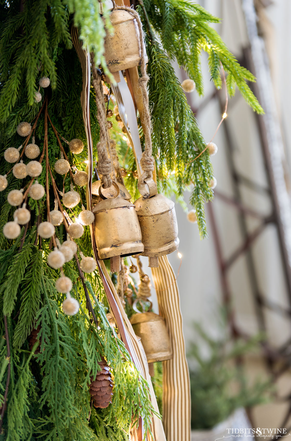 rustic gold french bells and striped ribbon hanging from fireplace mantel garland at Christmas