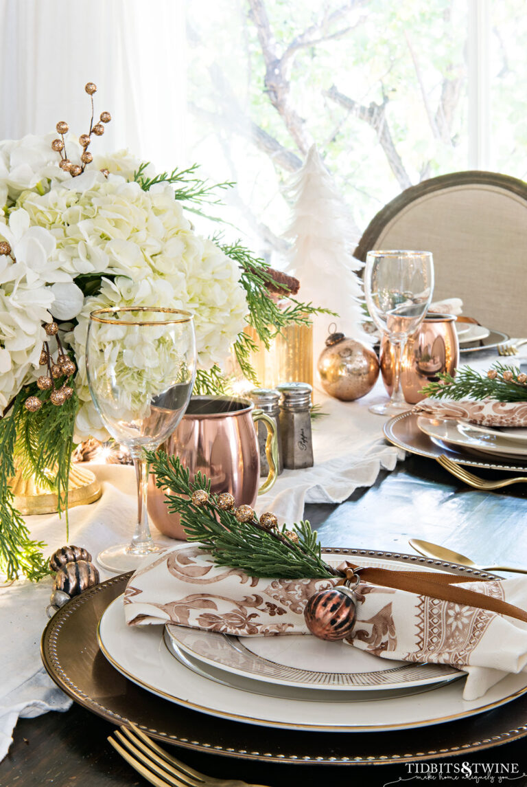 Christmas tablescape with gold and copper place settings and white hydrangea centerpiece
