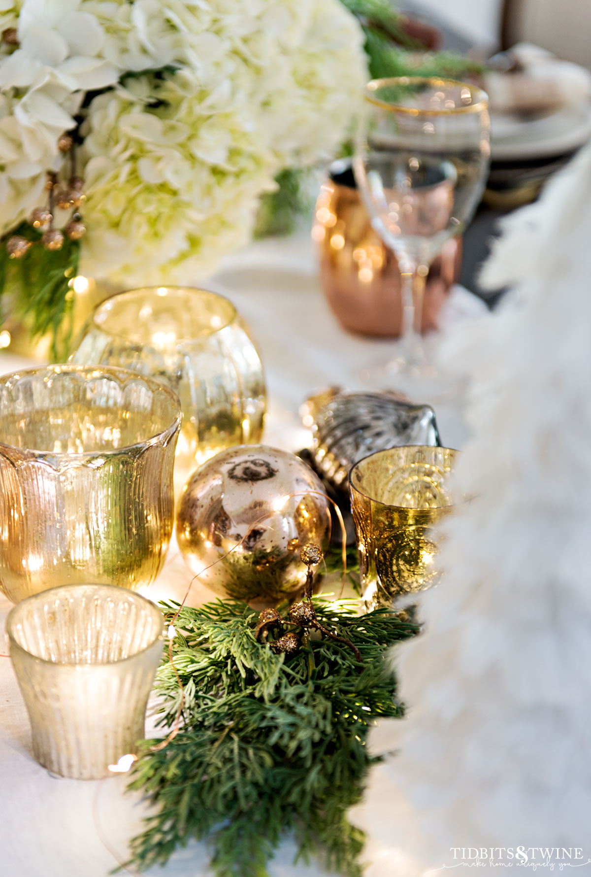 gold and silver christmas votives on dining table with ornaments and white feather tree