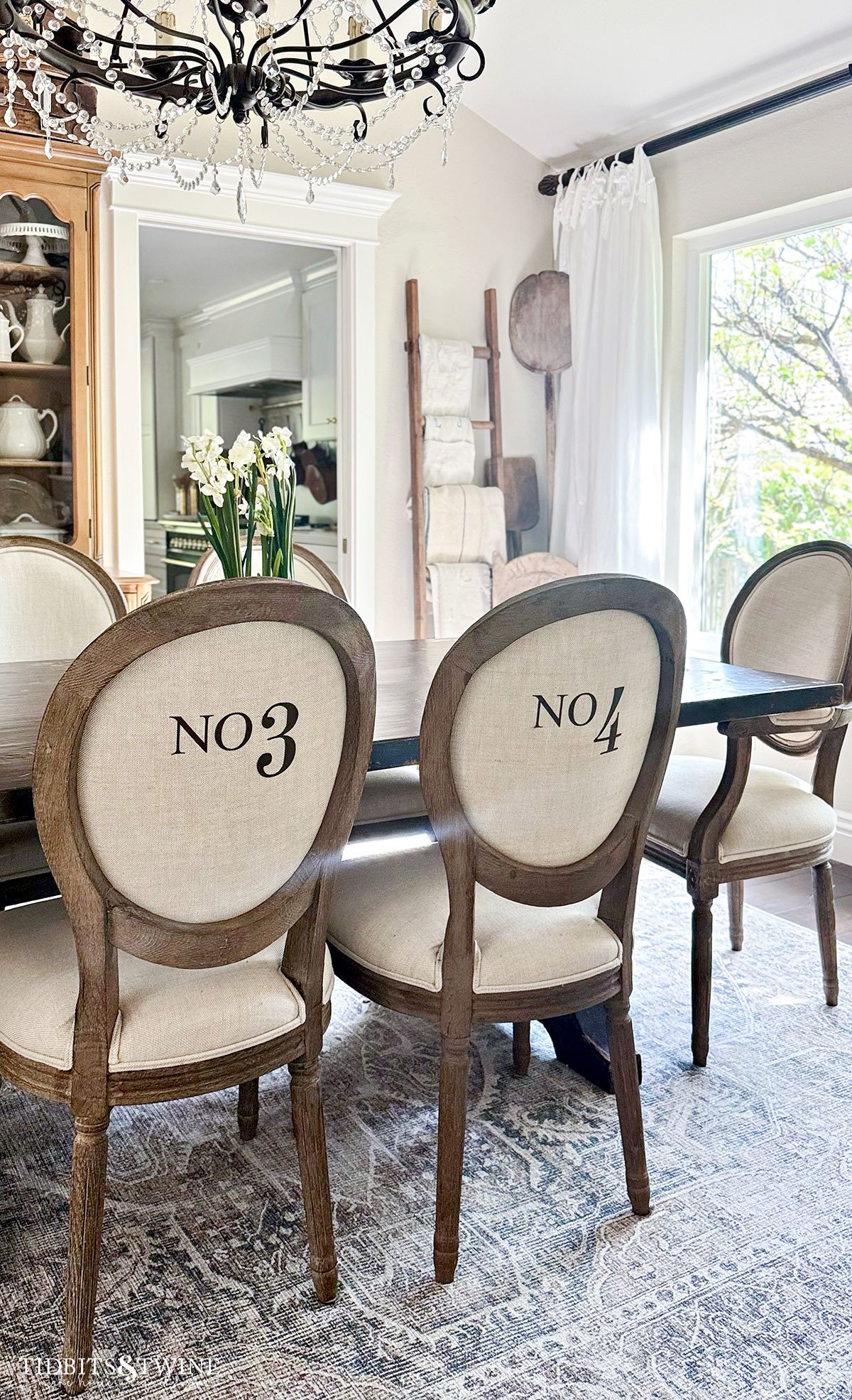 dining room with french linen chairs and crystal chandelier with trestle table