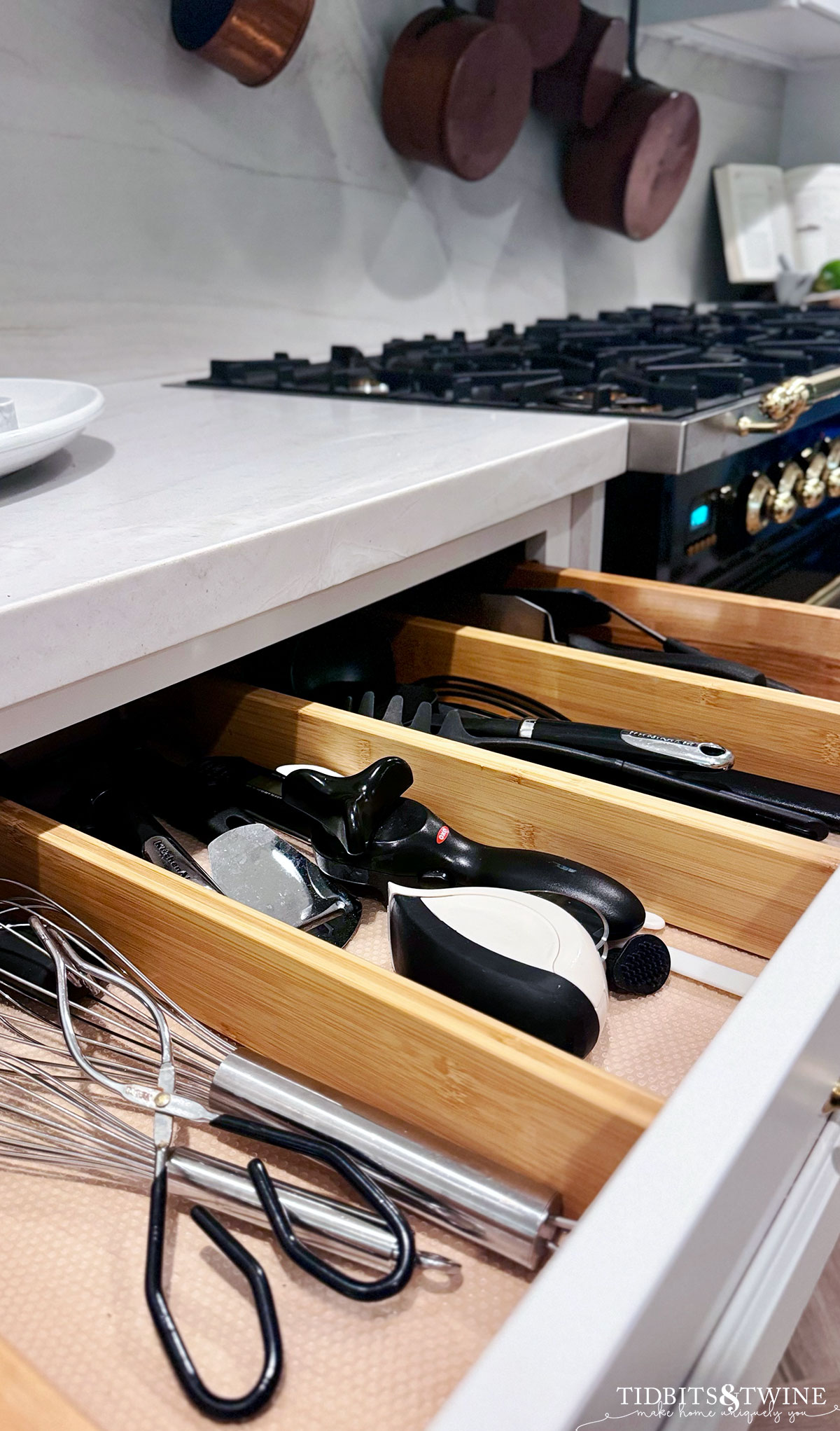 kitchen cooking utensil drawer with bamboo dividers and black utensils in white kitchen