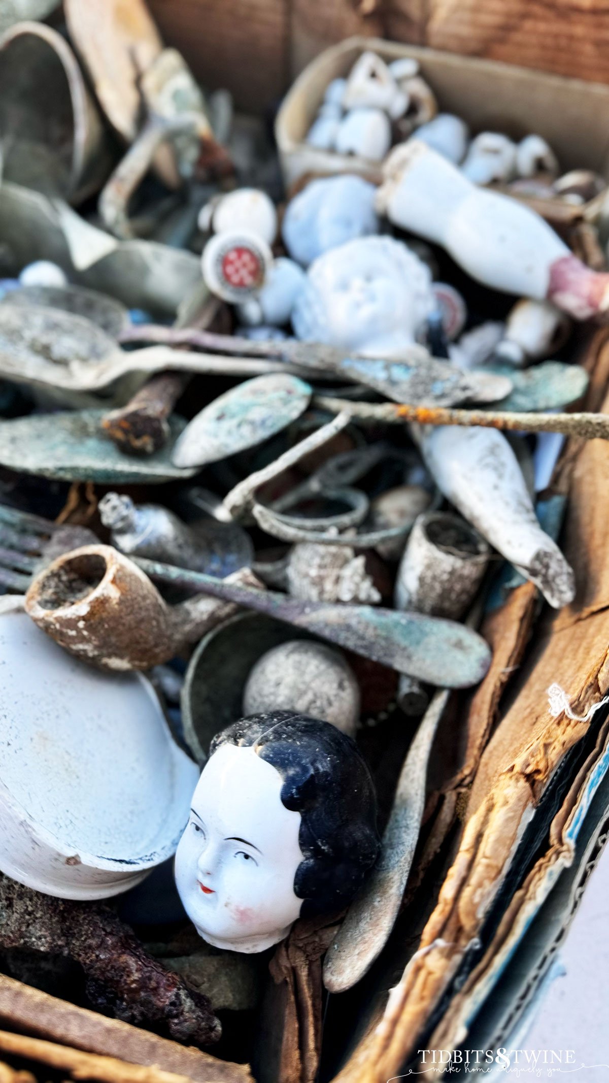 broken porcelain doll heads and arms in a basket with vintage spoons