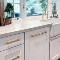 white kitchen cabinets with unlacquered brass pulls with text overlay for hardware placement guide