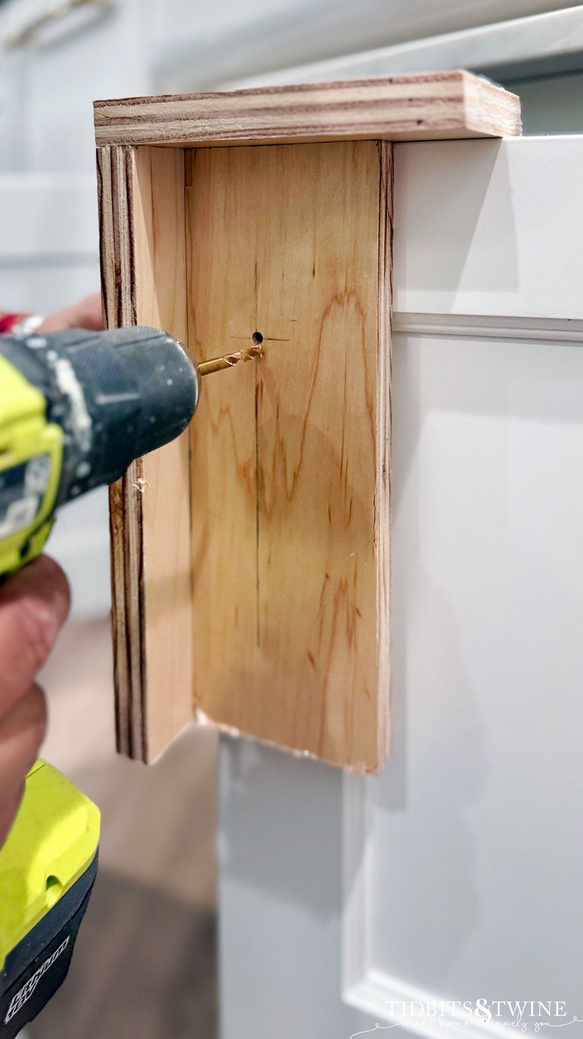 cabinet hardware template on a white door with hole for knob being drilled