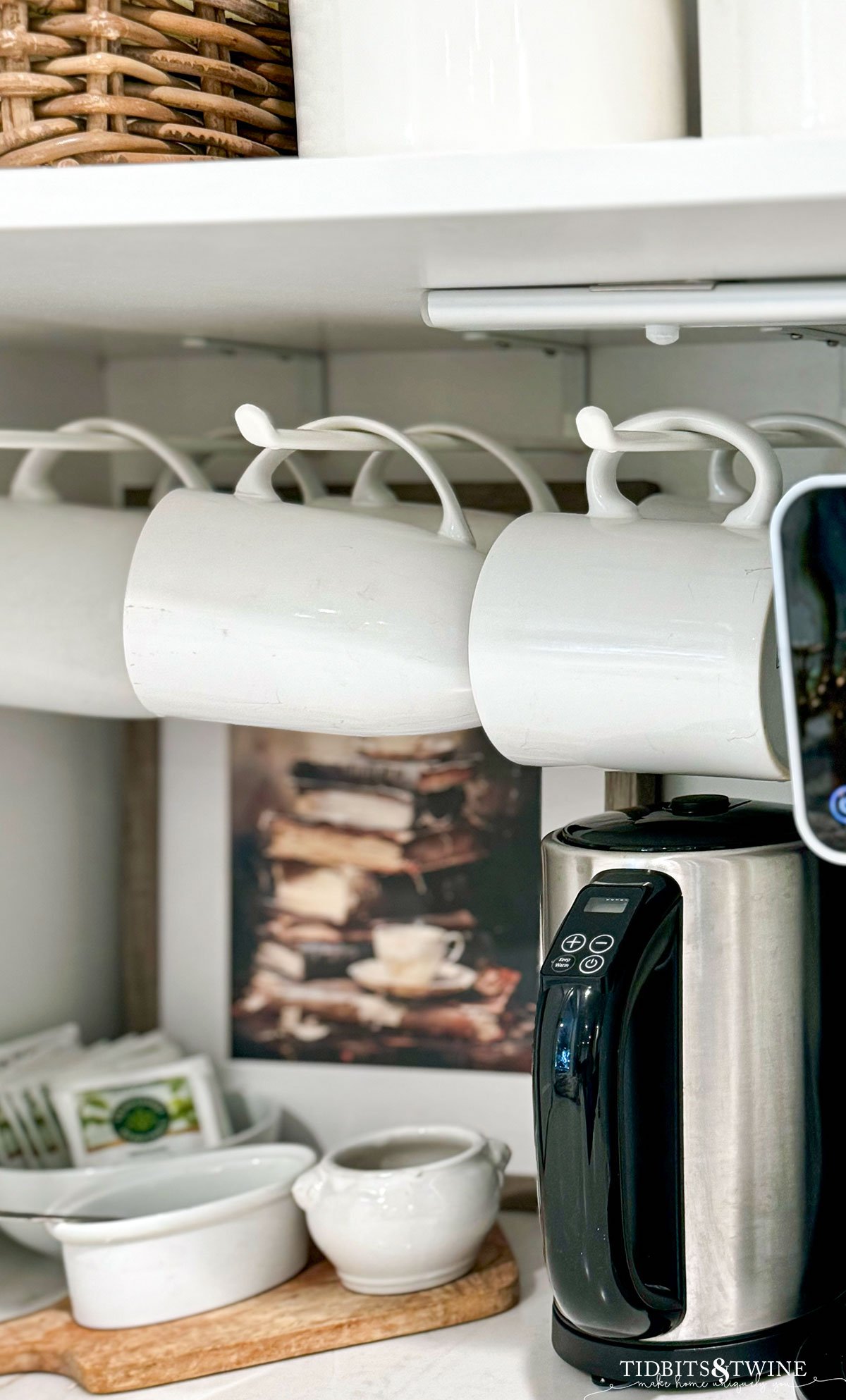 coffee cabinet with white mugs hanging from racks and tea supplies down below