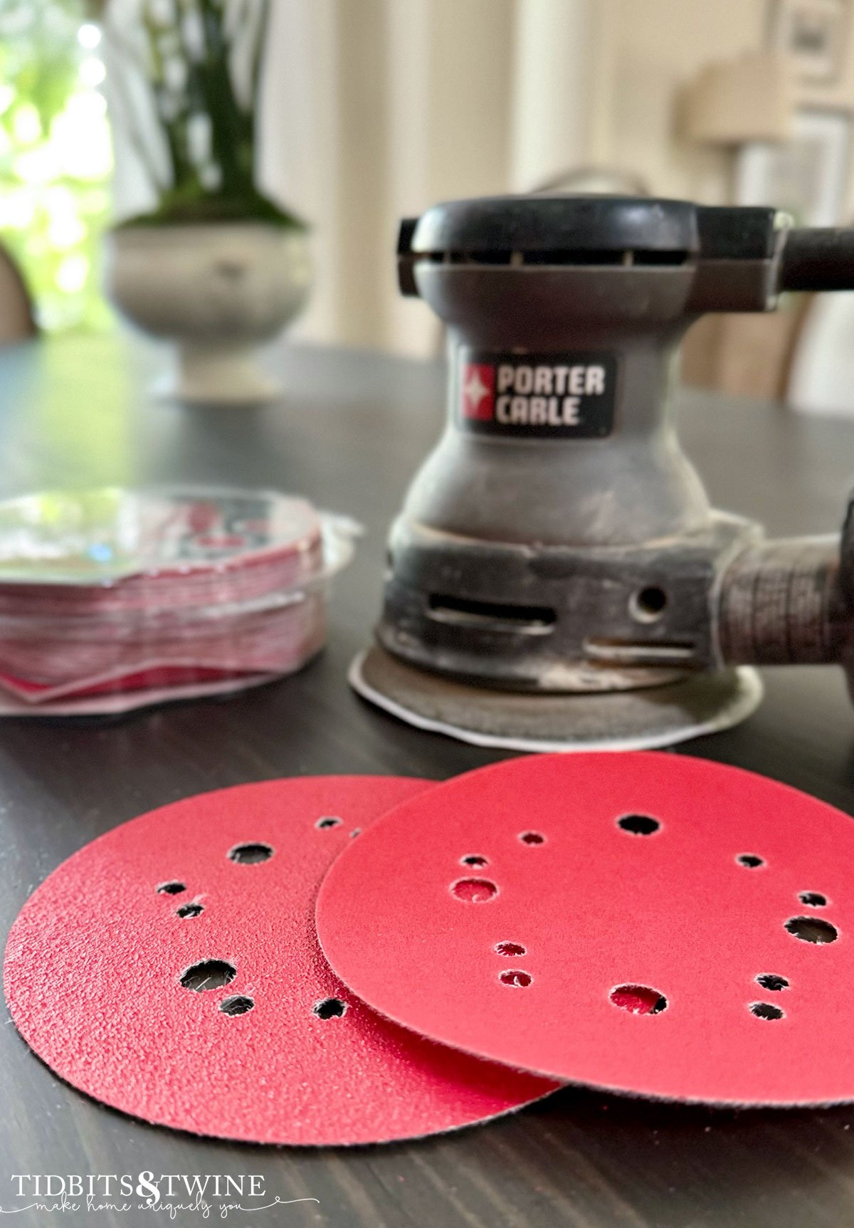 closeup of circular sander with two red sanding pads on table