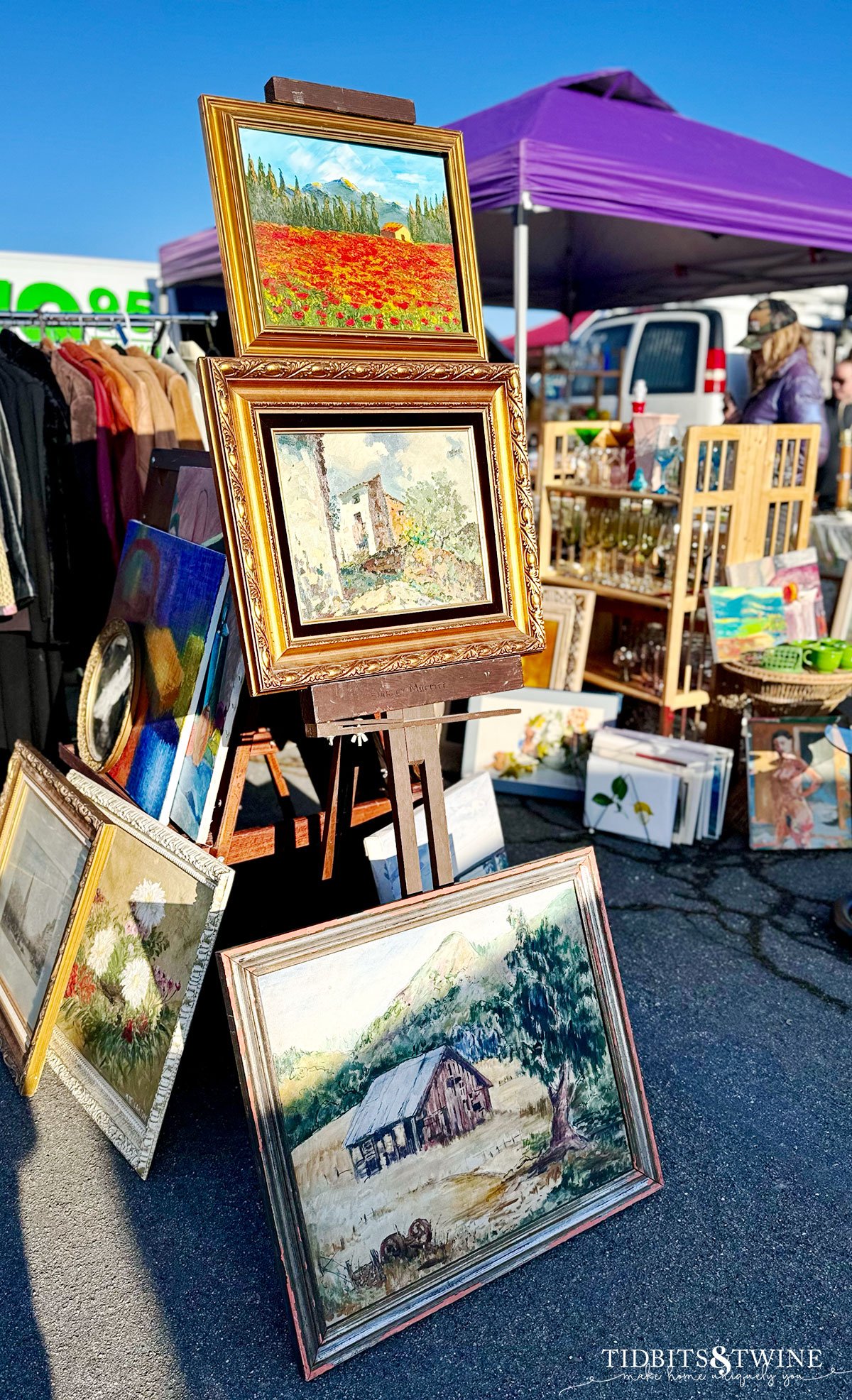 framed art on an easel and on ground at antique fair