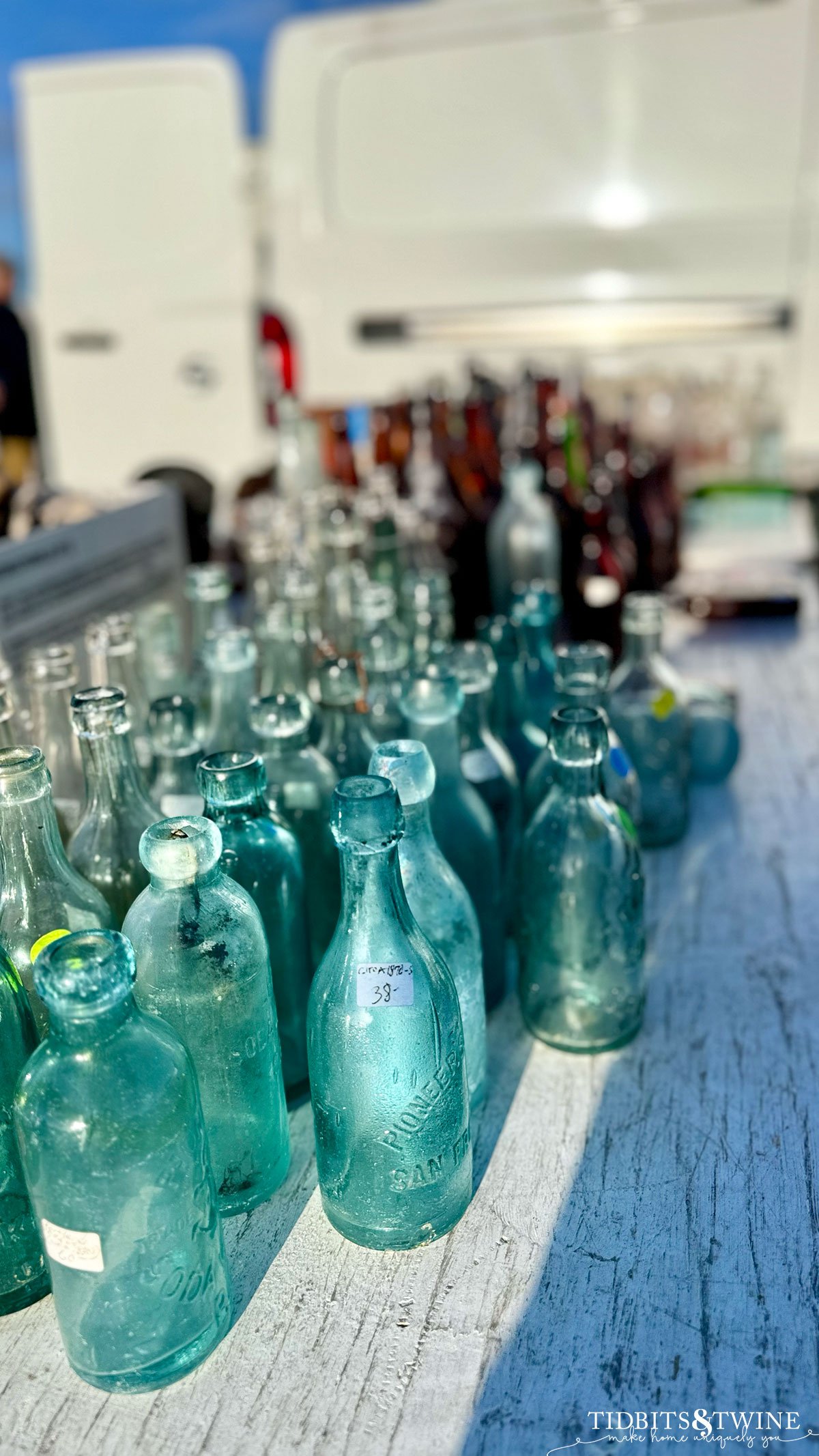 rows of blue and amber bottles lined up on a table for sale 