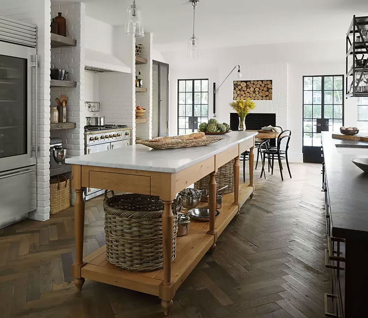 old world kitchen with french drapers table as a kitchen island and wood herringbone floors