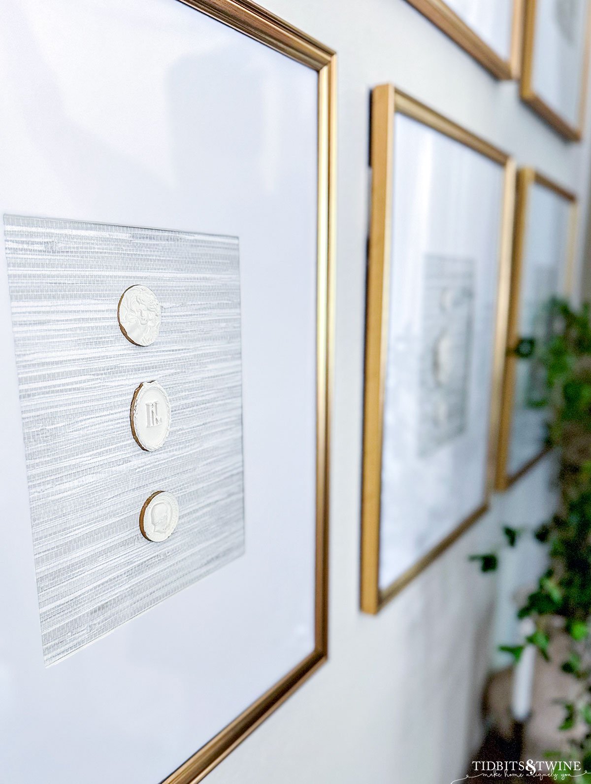 closeup of three diy intaglios in a gold frame with grasscloth wallpaper backing hanging on a wall