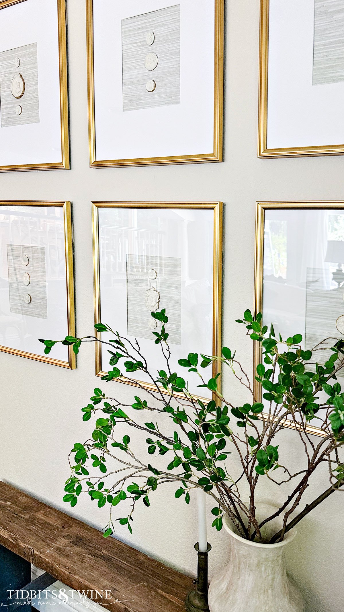 diy clay intaglios in six gold frames on the wall with a rustic bench beneath and greenery