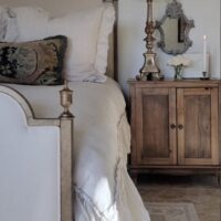 french bedroom with white linen bed and wood nightstand