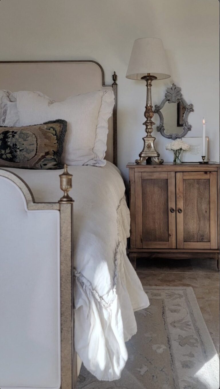 french bedroom with white linen bed and wood nightstand