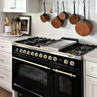 glossy black ilve range with gas top and pot rail above with copper pots