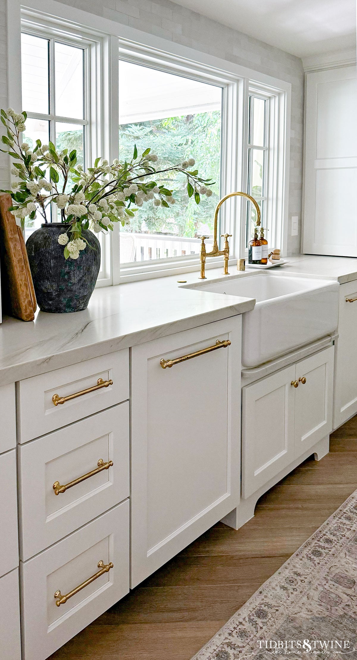 white kitchen cabinets with large window that extends down to the countertop and herringbone floors