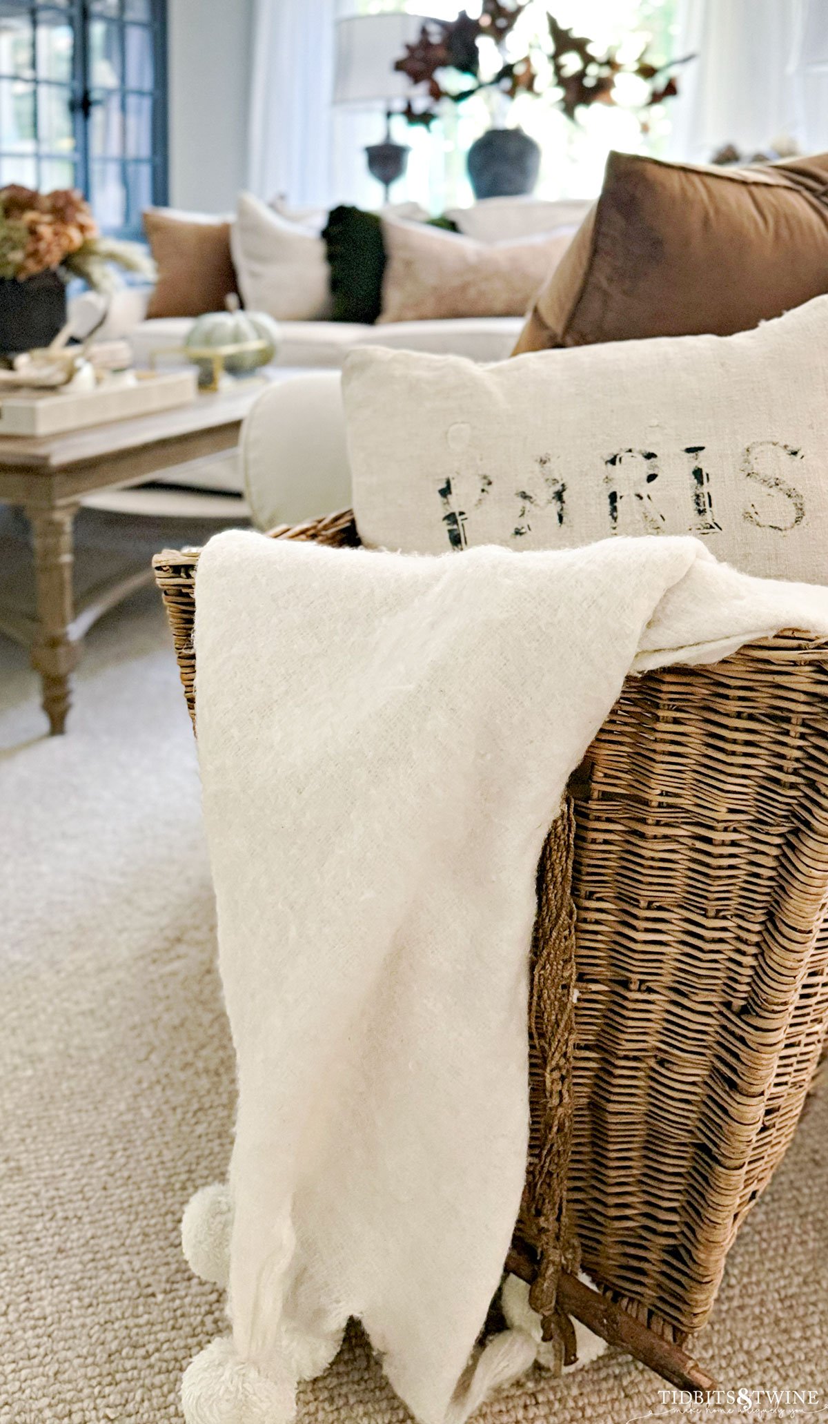 antique french basket holding a cream throw blanket at the end of a sofa - How to Style a Throw