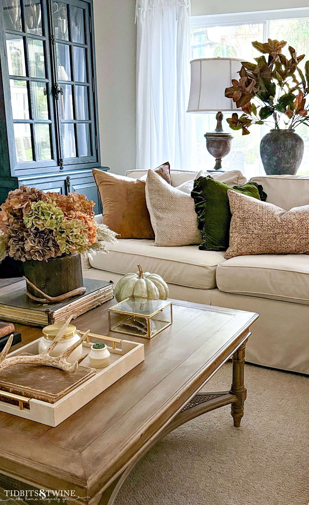 sofa with brown and green pillows and fall styled coffee table