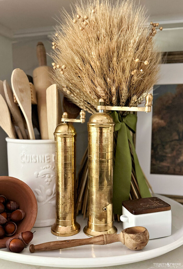 fall vignette in the kitchen with wheat bundle, gold pepper grinder, acorns and wooden utensils - Fall Vignette Ideas