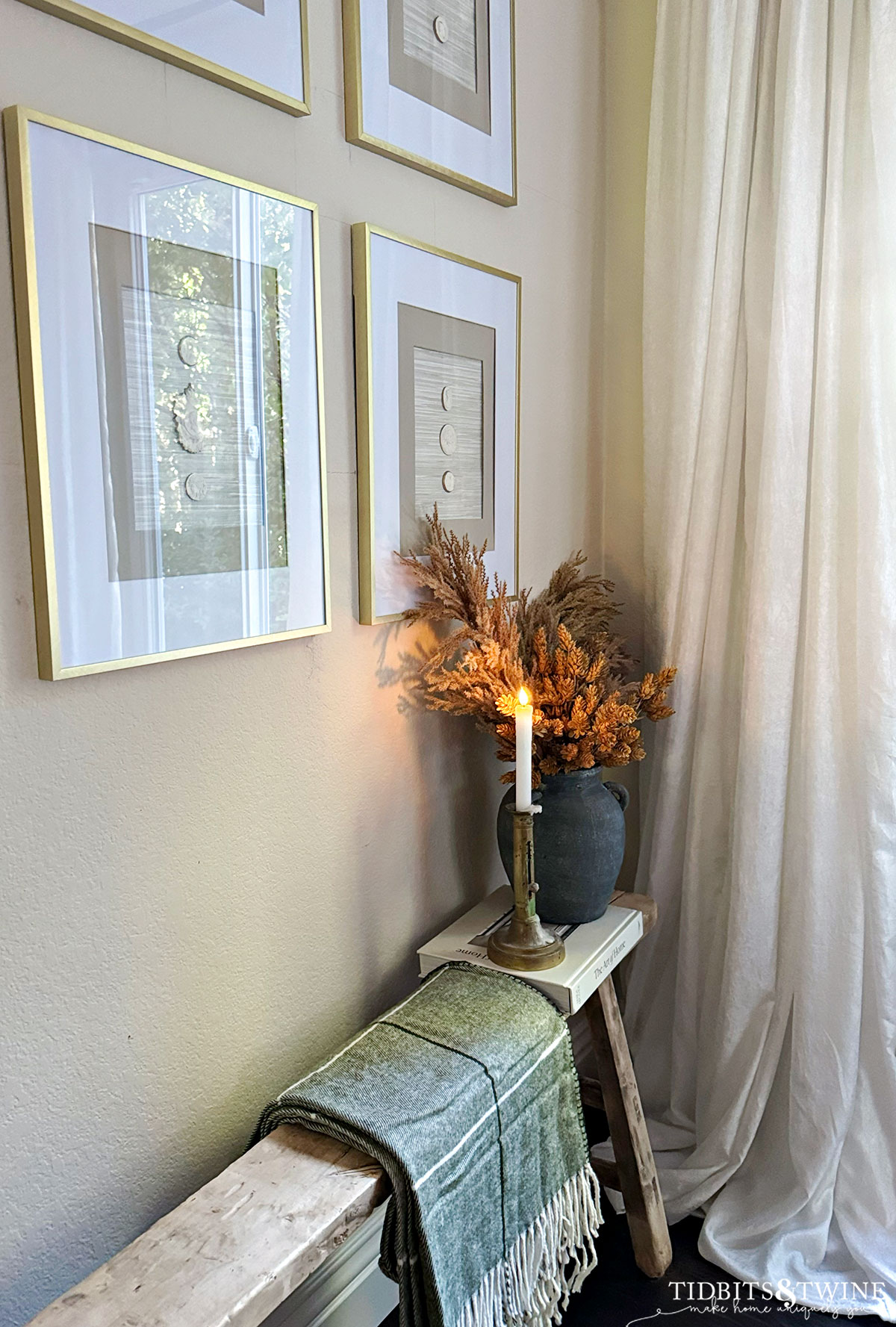 Entry vignette with framed intaglios, candle, and textured stems

