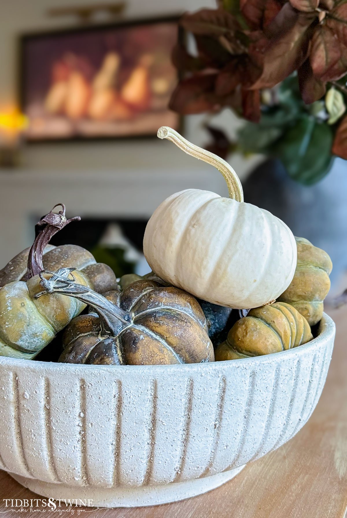 closeup of fluted bowl holding real and fake pumpkins with frame TV in background