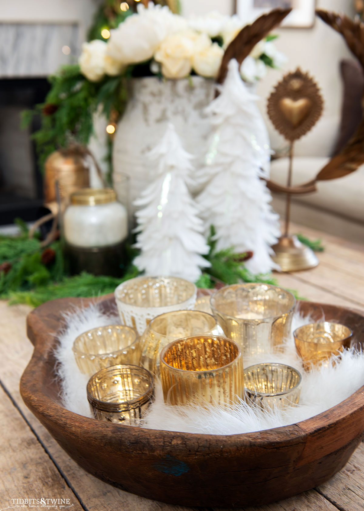 antique dough bowl filled with mercury votive holders and white feathers as part of christmas coffee table vignette