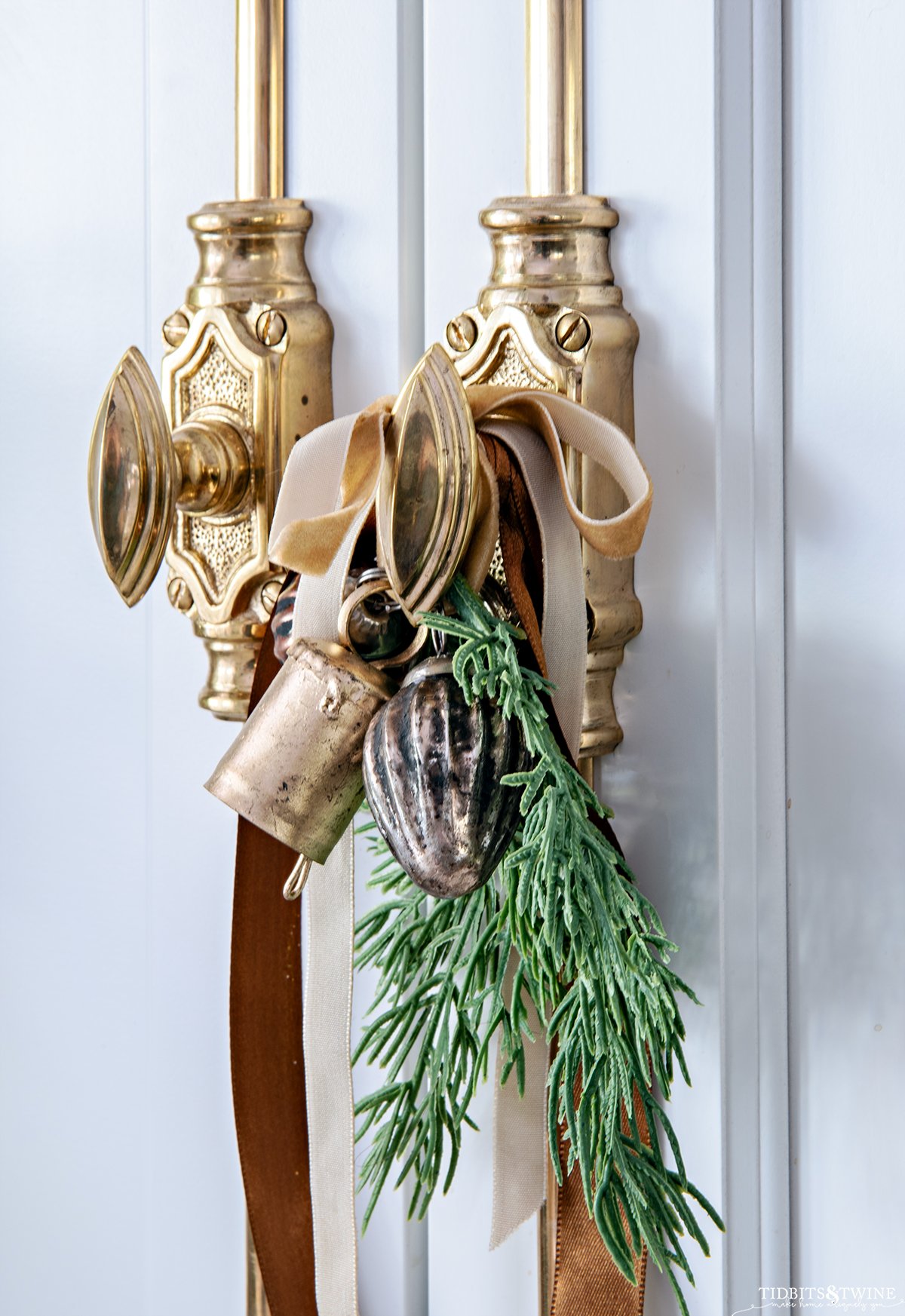gold brass cremone bolt styled for christmas with greenery small ornaments and ribbon