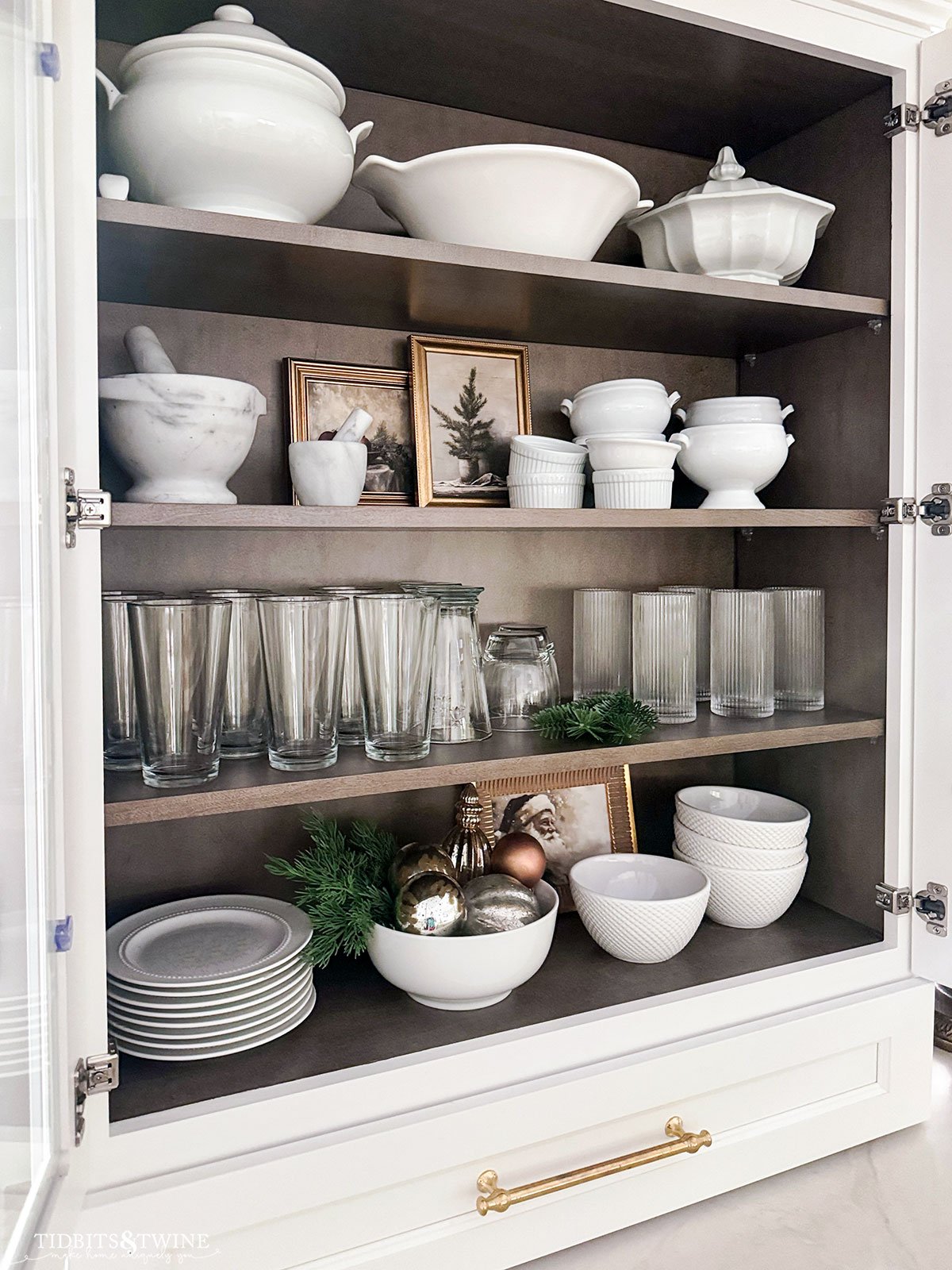 kitchen dish cabinet with white dishes and framed Christmas prints