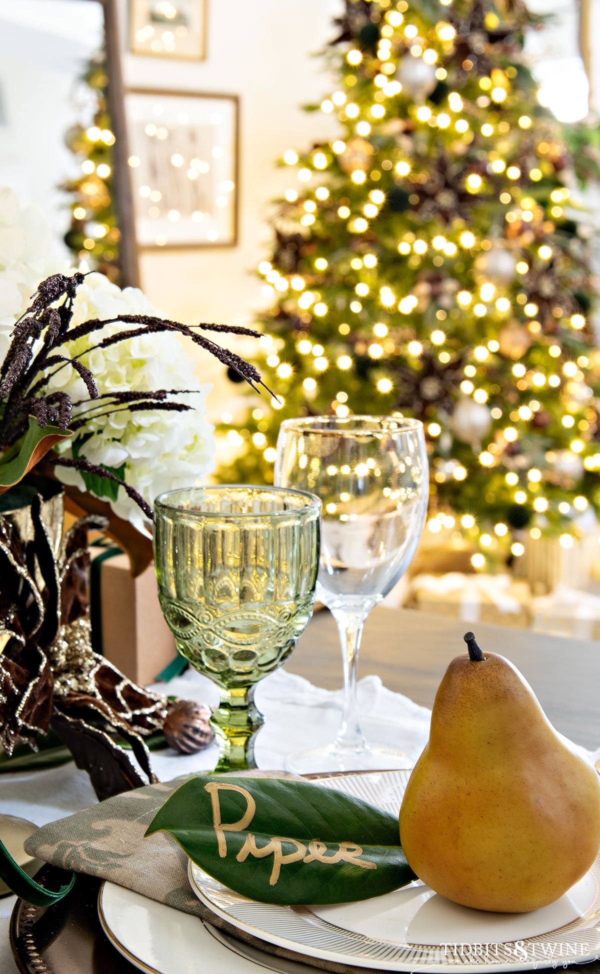 Christmas table place setting with magnolia and pear name card and Christmas tree in the background