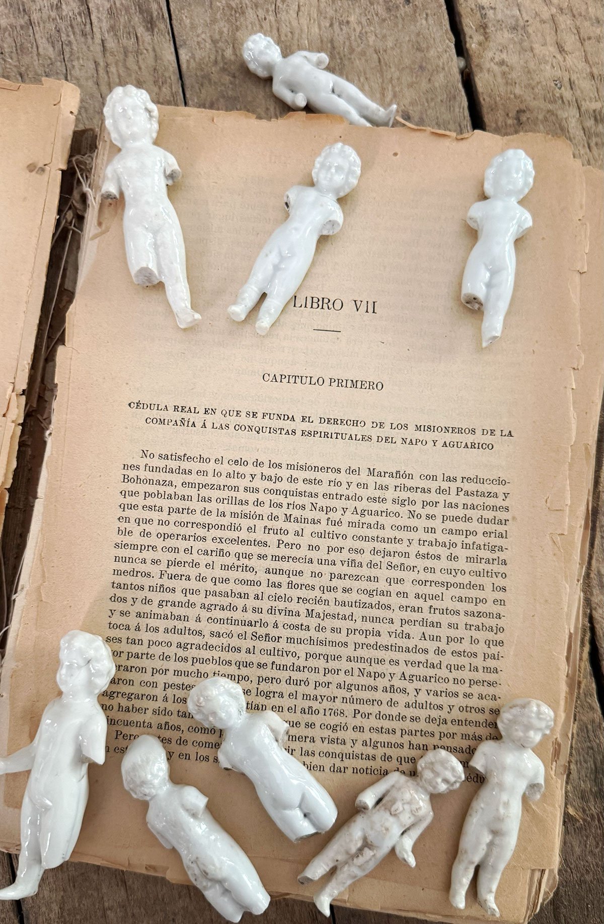 A small collection of antique Frozen Charlotte dolls styled on a vintage book — quirky antiques that add curiosity and charm to home decor.