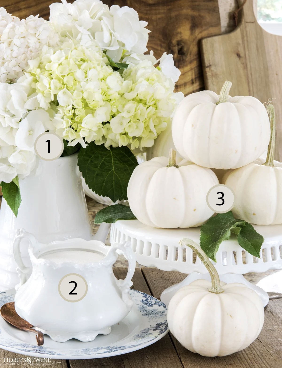 Fall display of white hydrangeas and white pumpkins styled in a group of three following the rule of three decorating principle