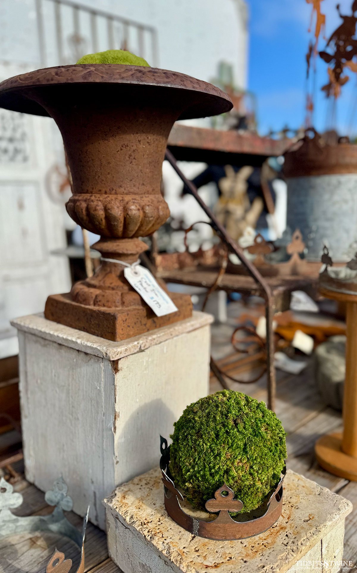 Cast iron urn with faux moss and a decorative rusty crown on top, styled for garden decor.
