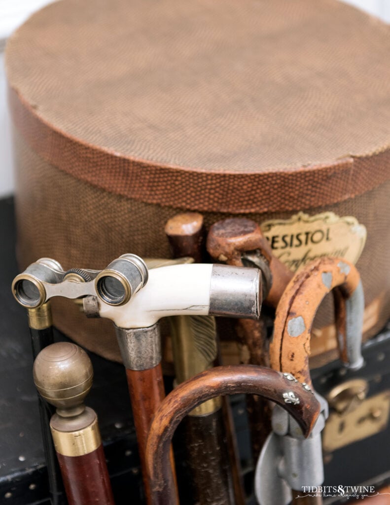 Collection of antique gadget canes displayed in a galvanized bucket — unusual everyday objects styled as quirky antique decor.