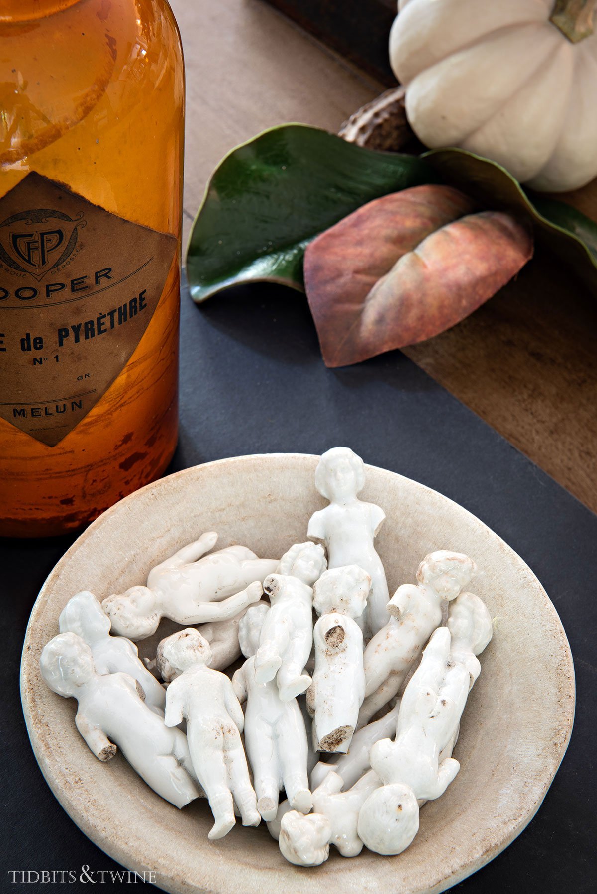 marble bowl filled with vintage Frozen Charlotte dolls — collected and personal decor.