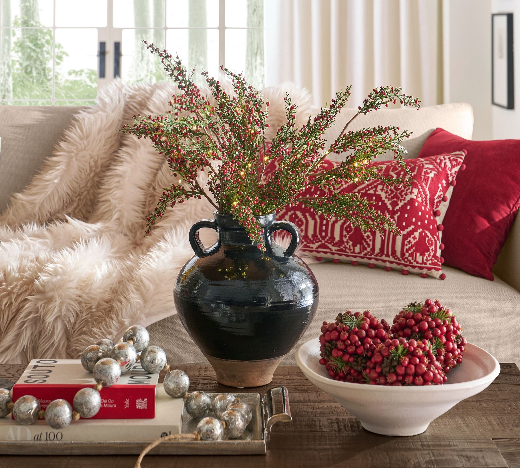 Coffee table vignette with black vase, books, and ornaments on a tray — shows how trays anchor decor.