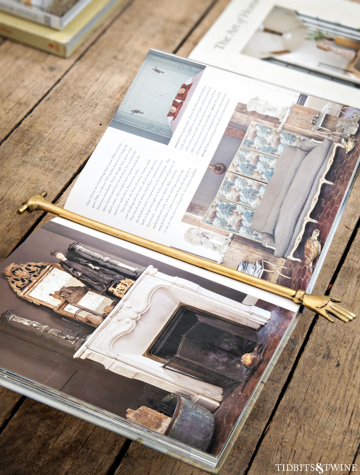 Open design book on a rustic coffee table held with a decorative brass hand bookmark