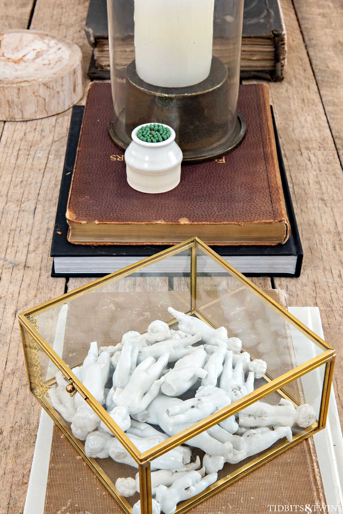 Glass display box filled with antique Frozen Charlotte dolls styled on a coffee table for a personal, collected touch