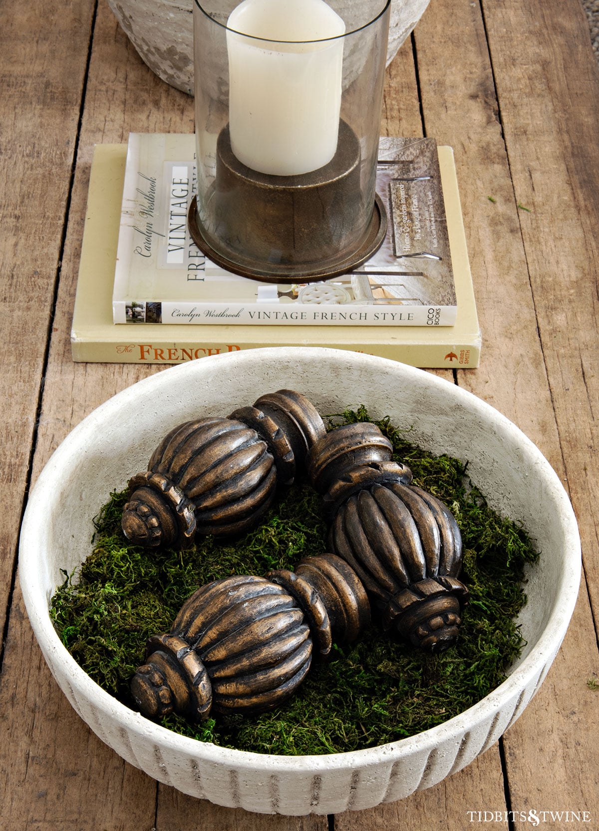 Decorative bowl filled with moss and carved finials on a rustic wood coffee table