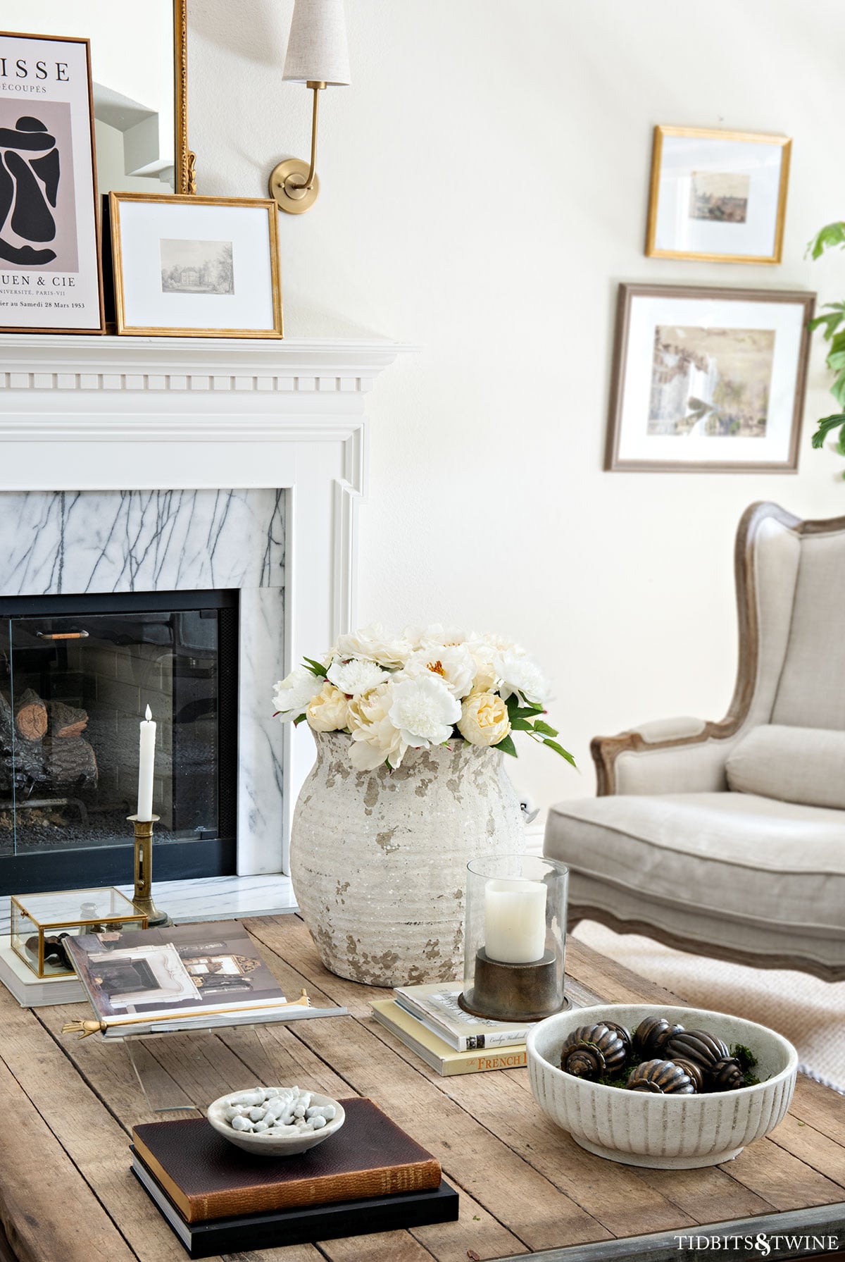 Styled living room coffee table with books, a rustic vase of white flowers, and layered decorative accents for a polished, finished look