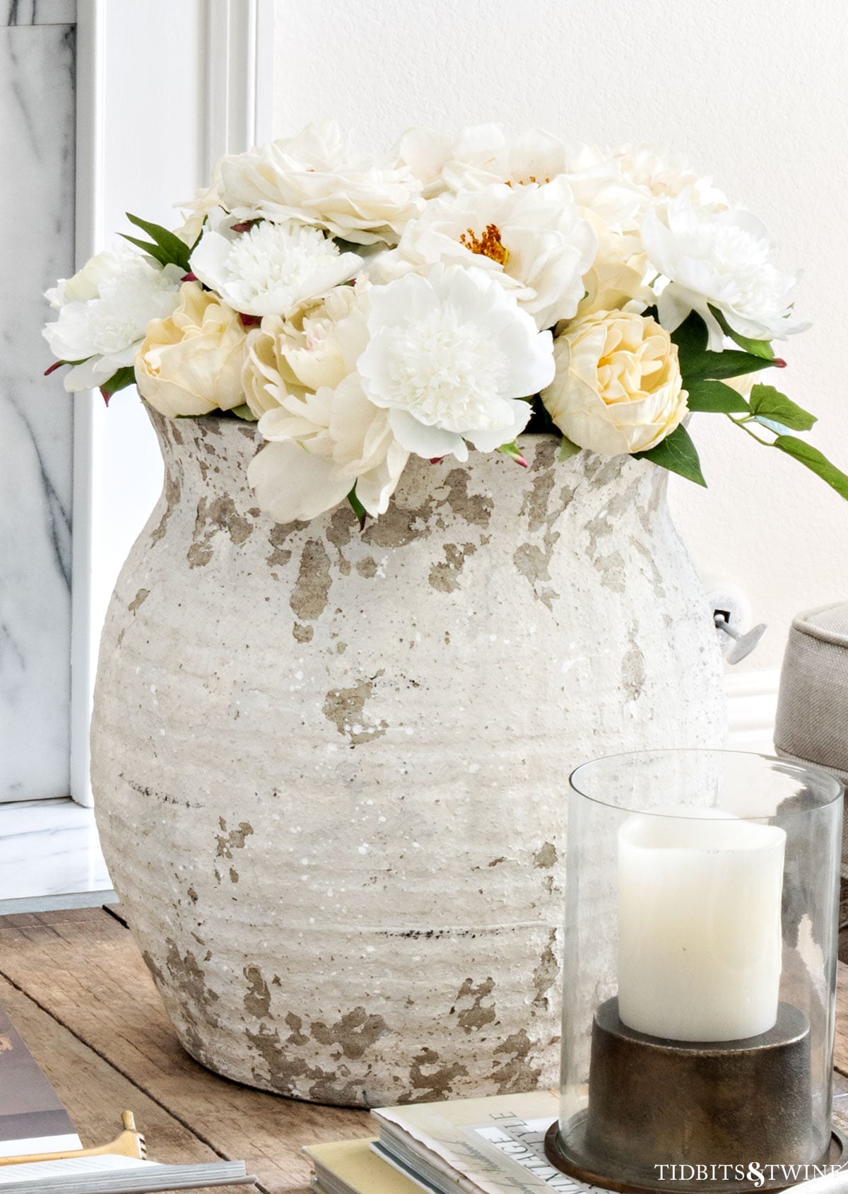 Coffee table decor with an oversized vase of white flowers as a focal point in a neutral living room
