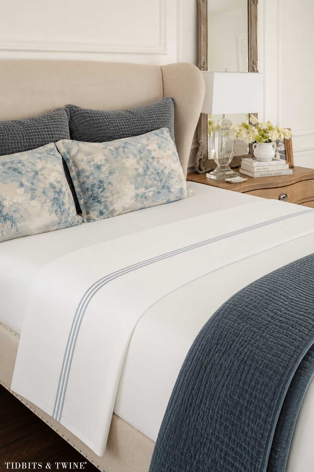 White cotton sheets with blue hotel-style banding on a neatly made bed