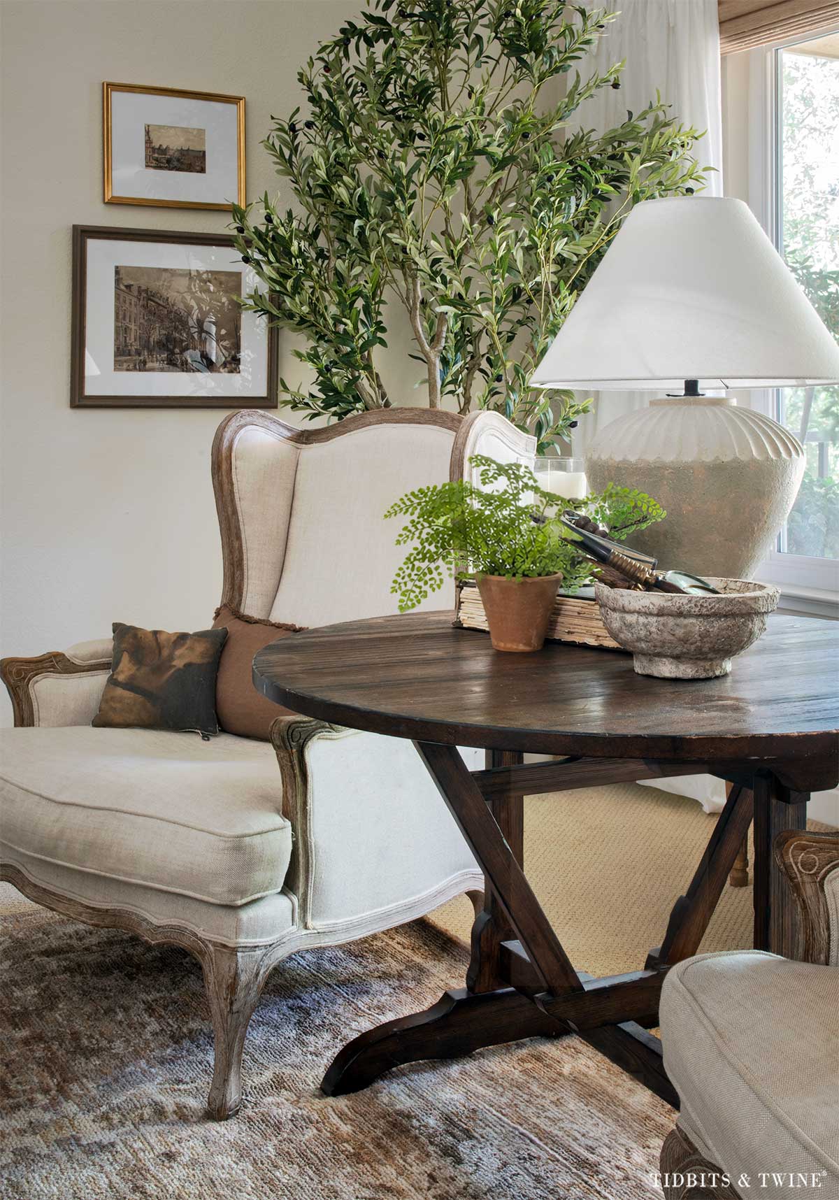 Antique wine-tasting table used as a side table between two living room chairs