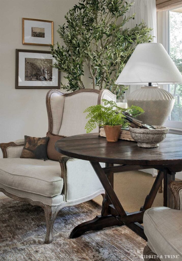 Antique wine-tasting table used as a side table between two living room chairs