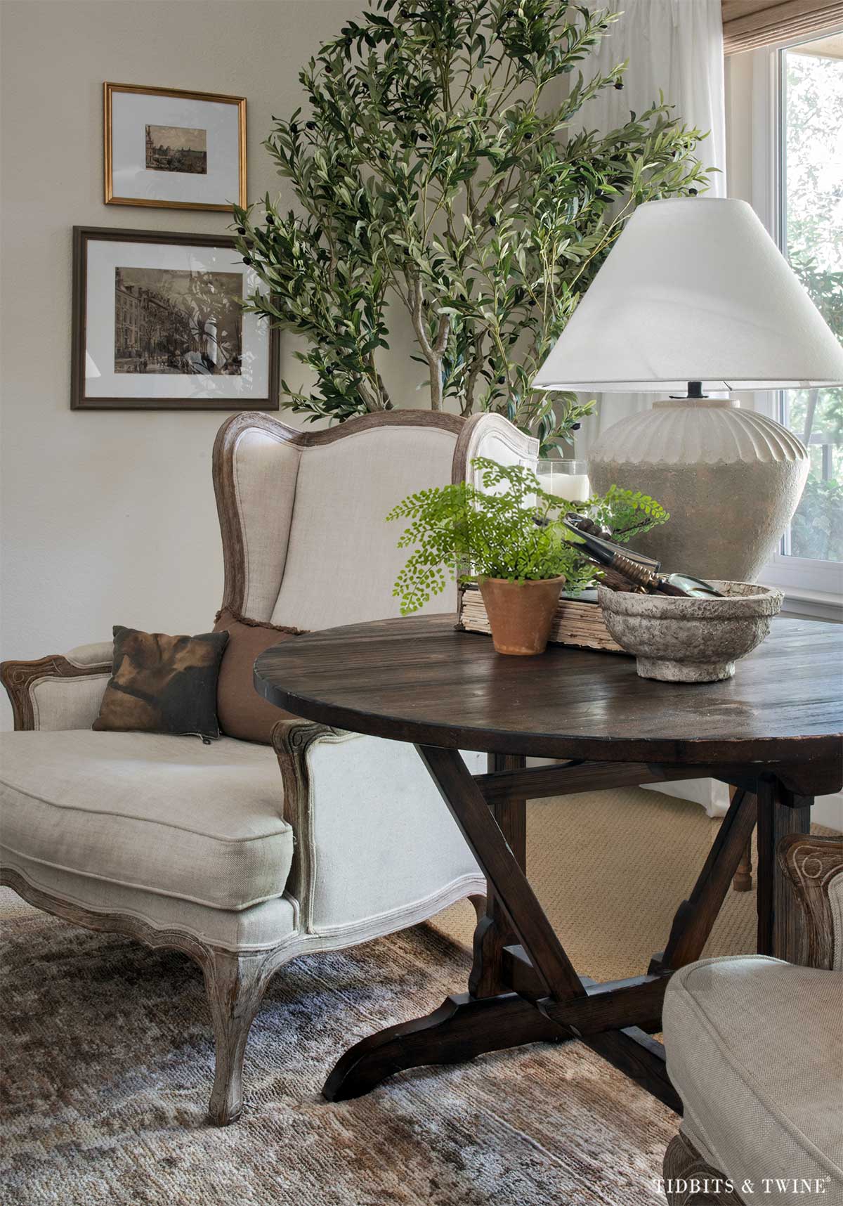 Antique wine-tasting table used as a side table between two living room chairs