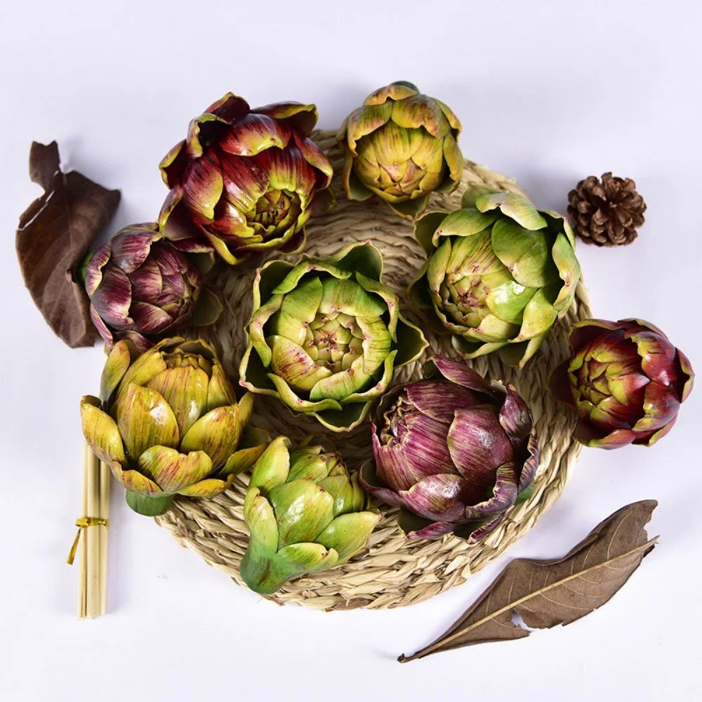 Green and purple artichokes arranged in a woven basket with dried leaves and pinecones
