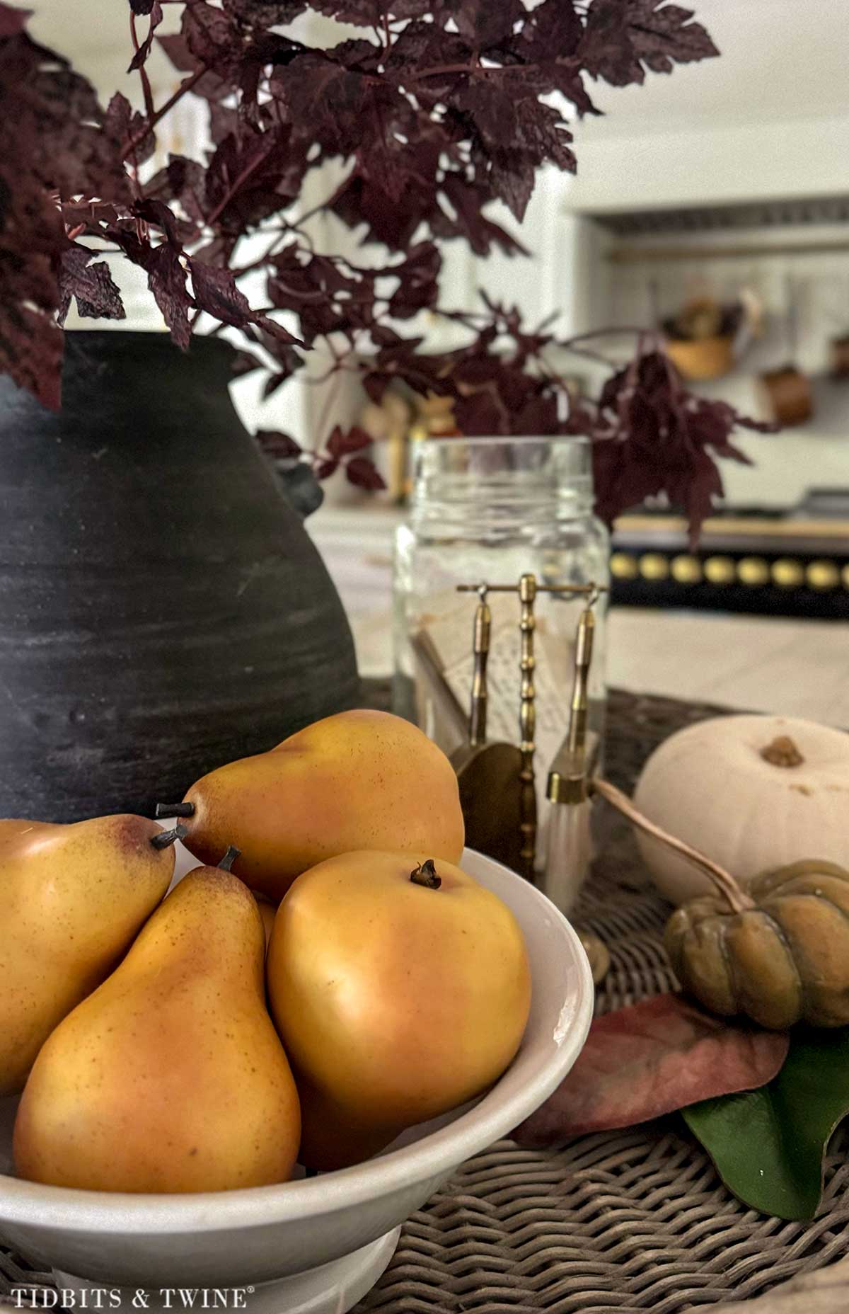 Realistic faux pears displayed with pumpkins and vintage kitchen accessories for fall