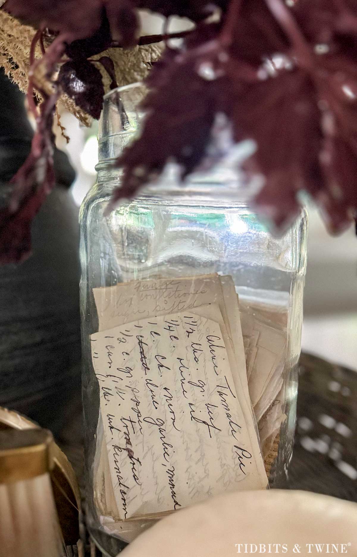 Vintage glass jar filled with handwritten family recipe cards on a kitchen island
