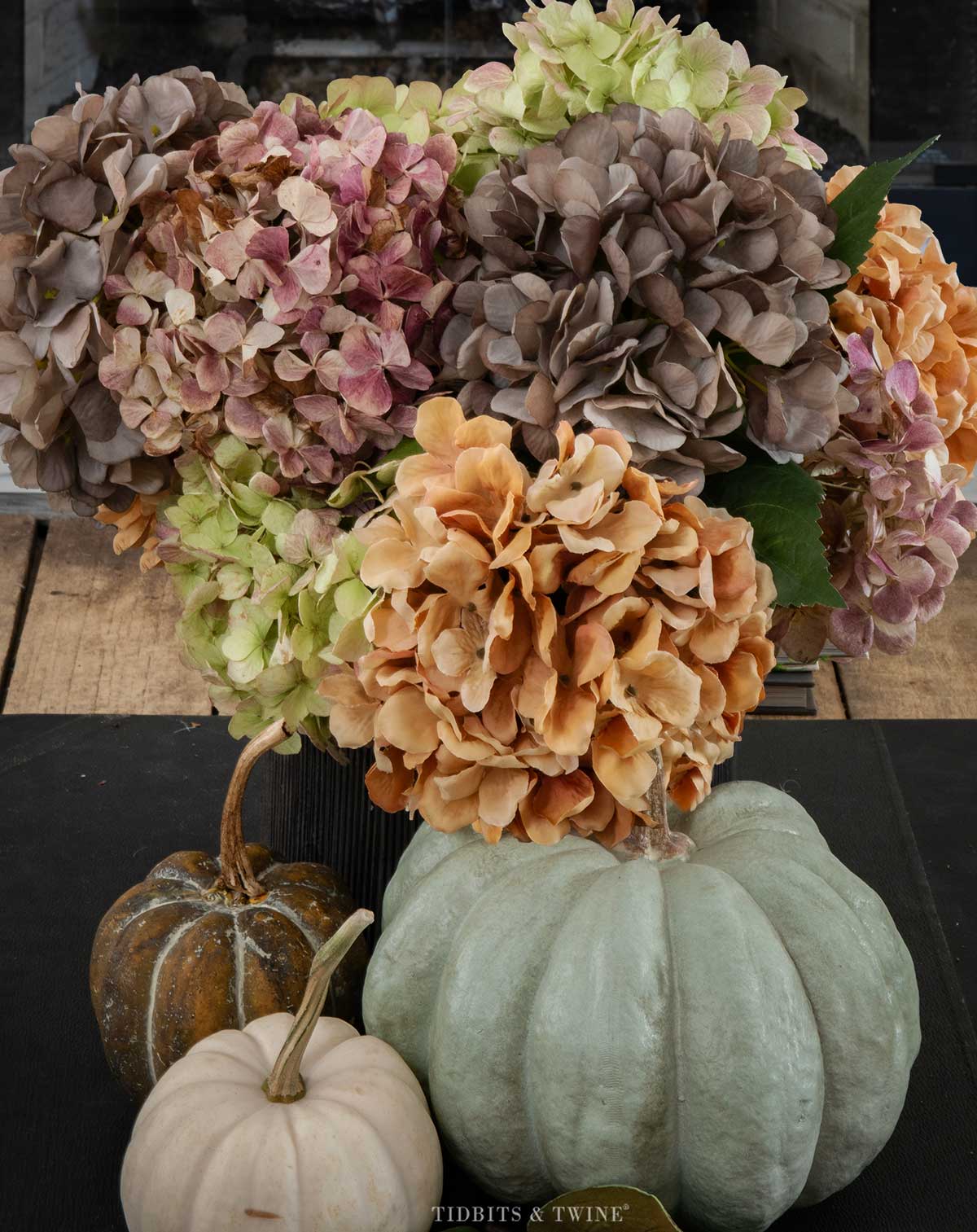 Dried hydrangeas and pumpkins arranged on a black book on the coffee table