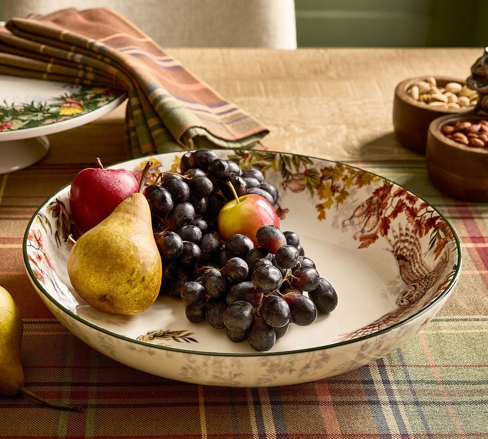 Dark grapes, pears, and pomegranates arranged in a vintage patterned serving bowl