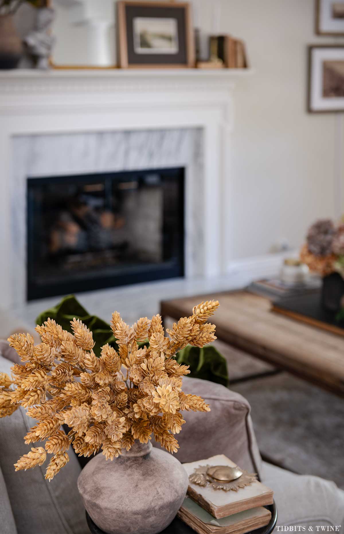 Vase of golden faux dried stems beside an upholstered chair in the living room